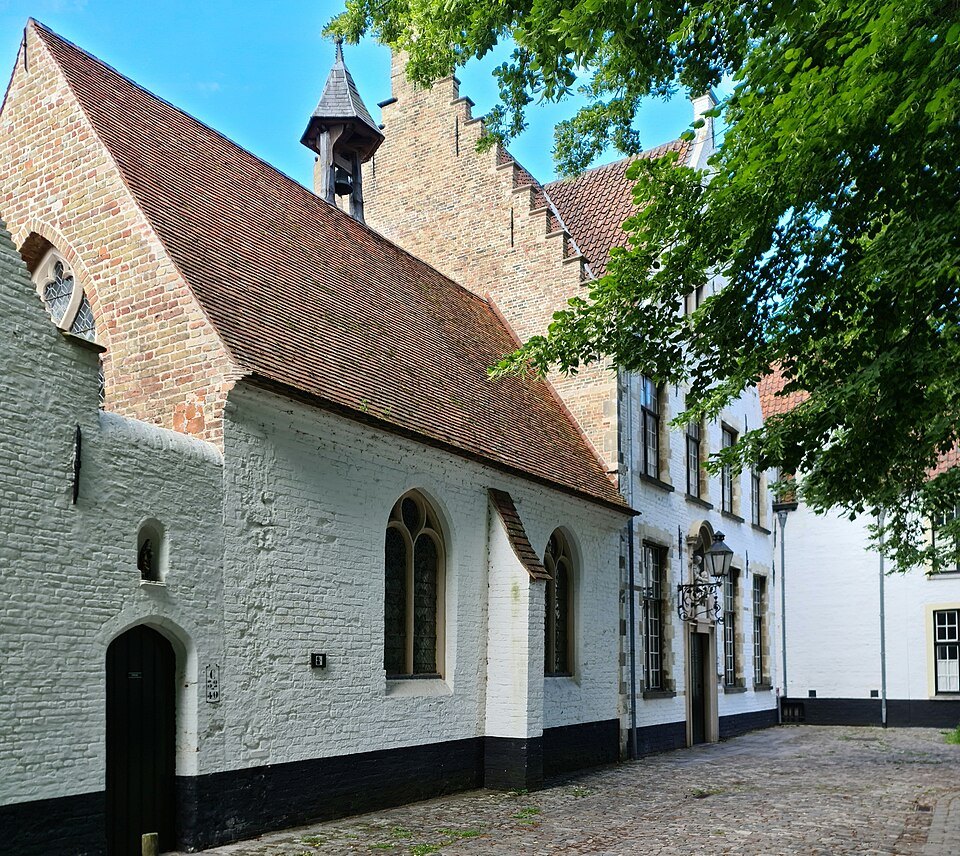The whitewashed side of the church beside houses on the cobbles