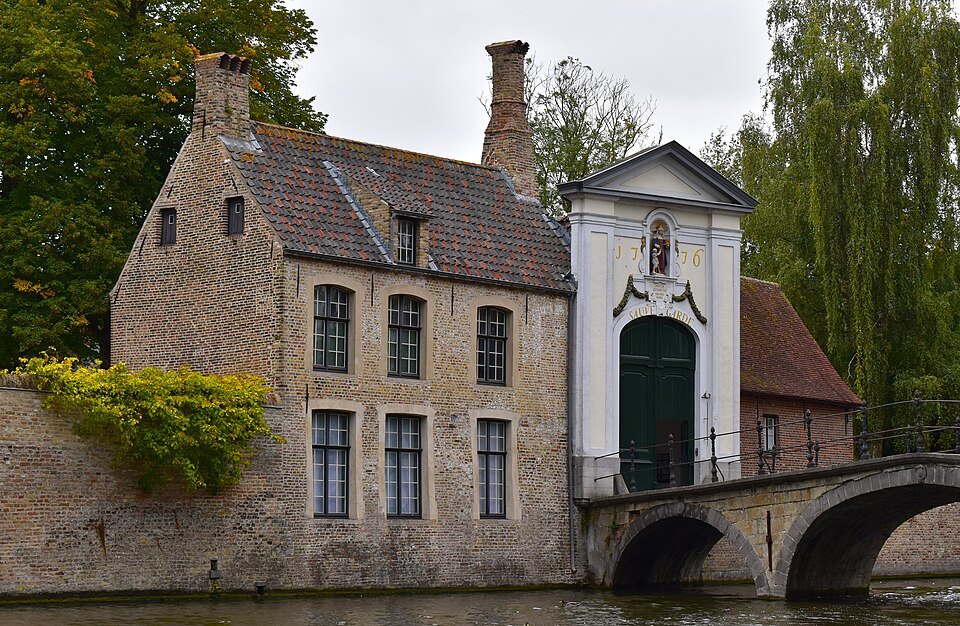 The bridge and white gateway into the Beguinage beside a brick house