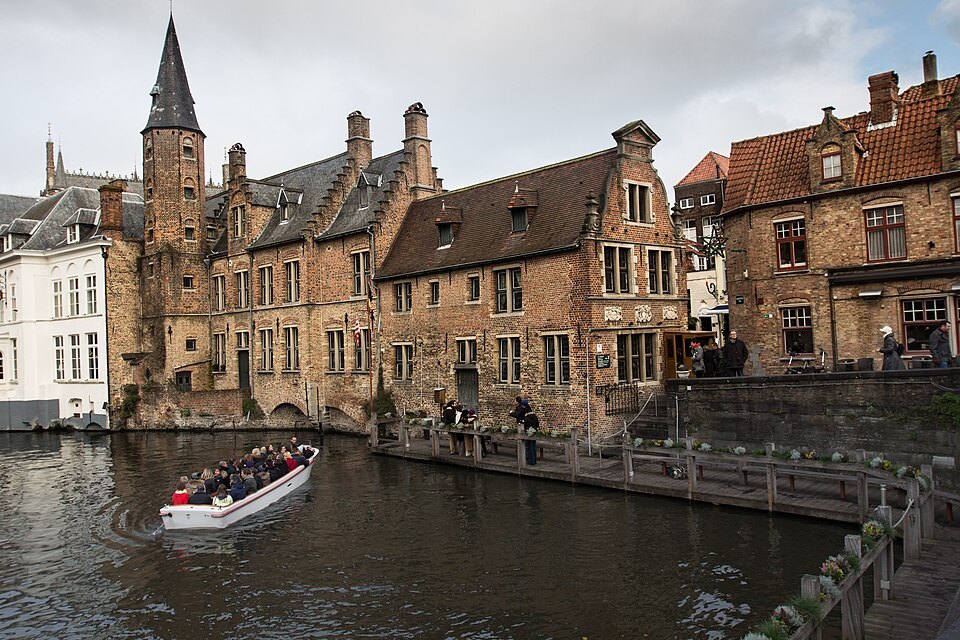 A tour boat gliding past old brick houses at a canal corner