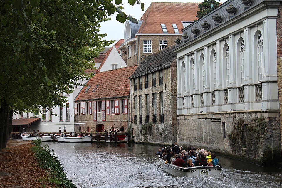 A boat full of visitors under the trees on the Dijver