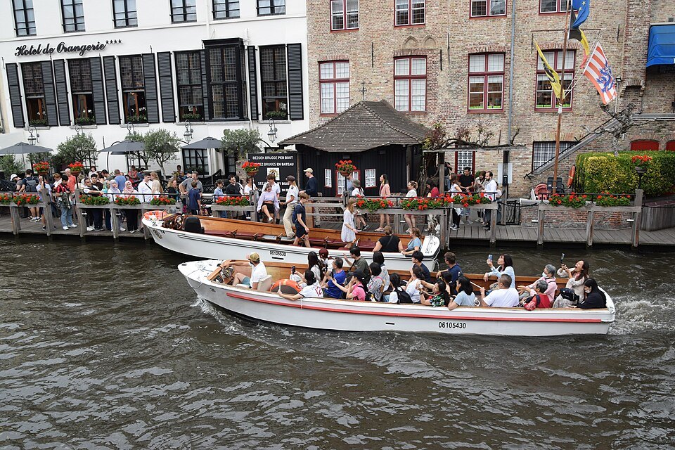 Passengers in open boats beside a landing stage crowded with visitors