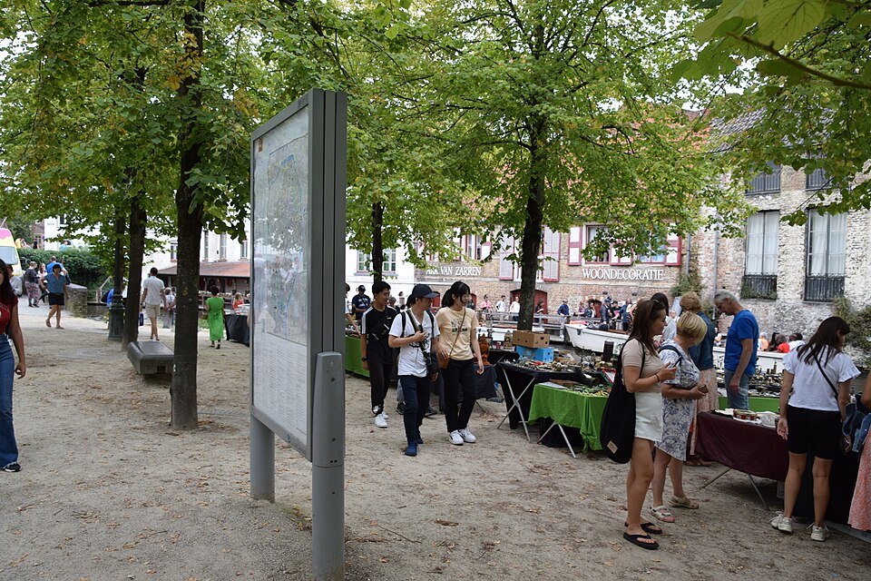 Stalls of a flea market under the trees along the Dijver