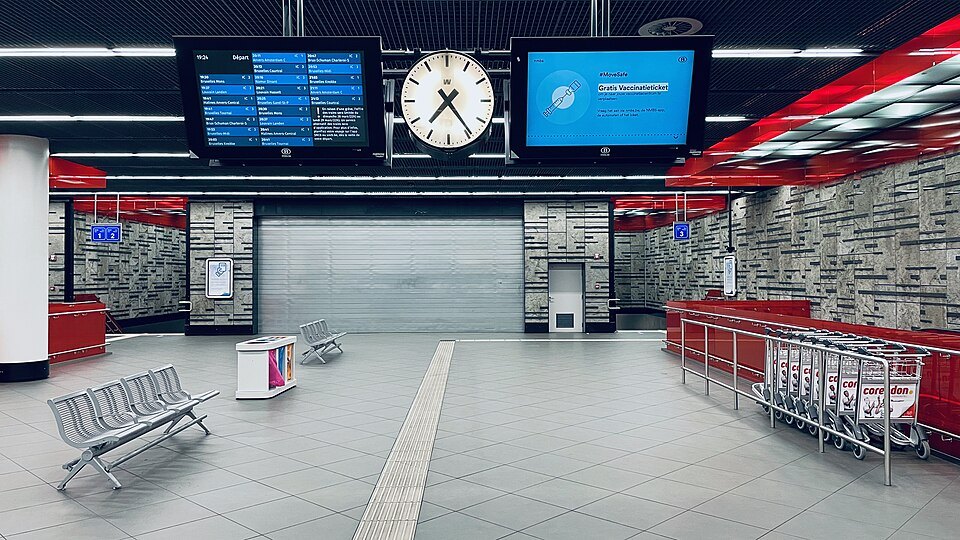 The station hall below Brussels Airport, with departure boards and a clock