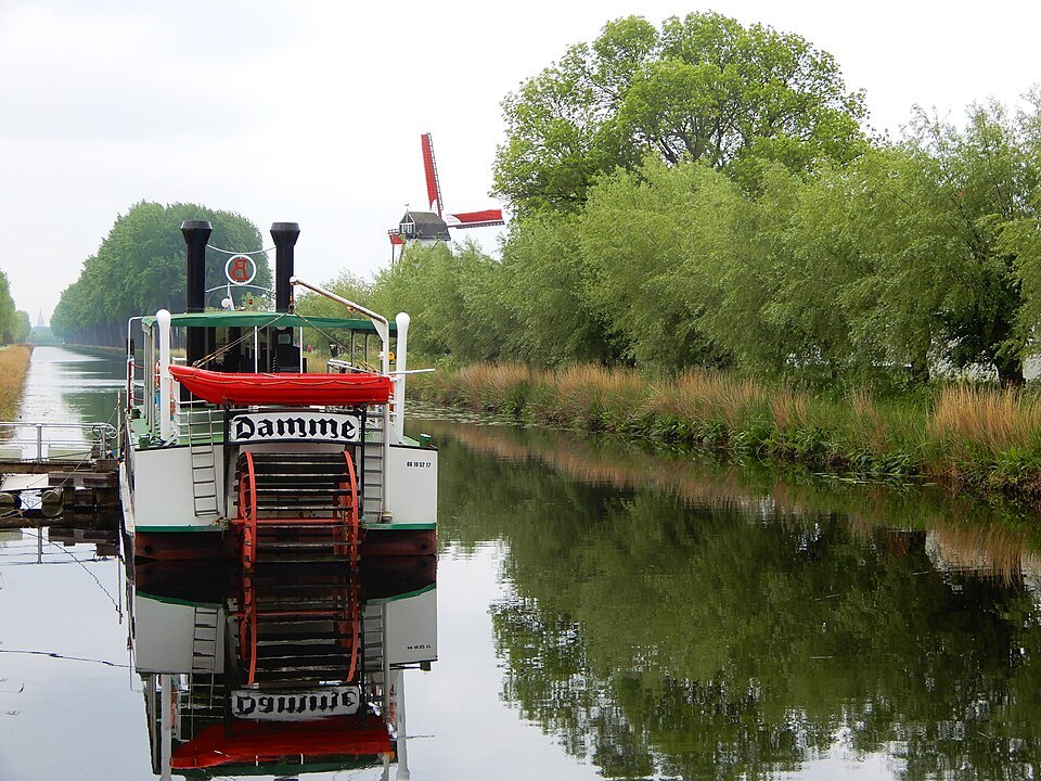 The paddle steamer moored on the canal near a windmill