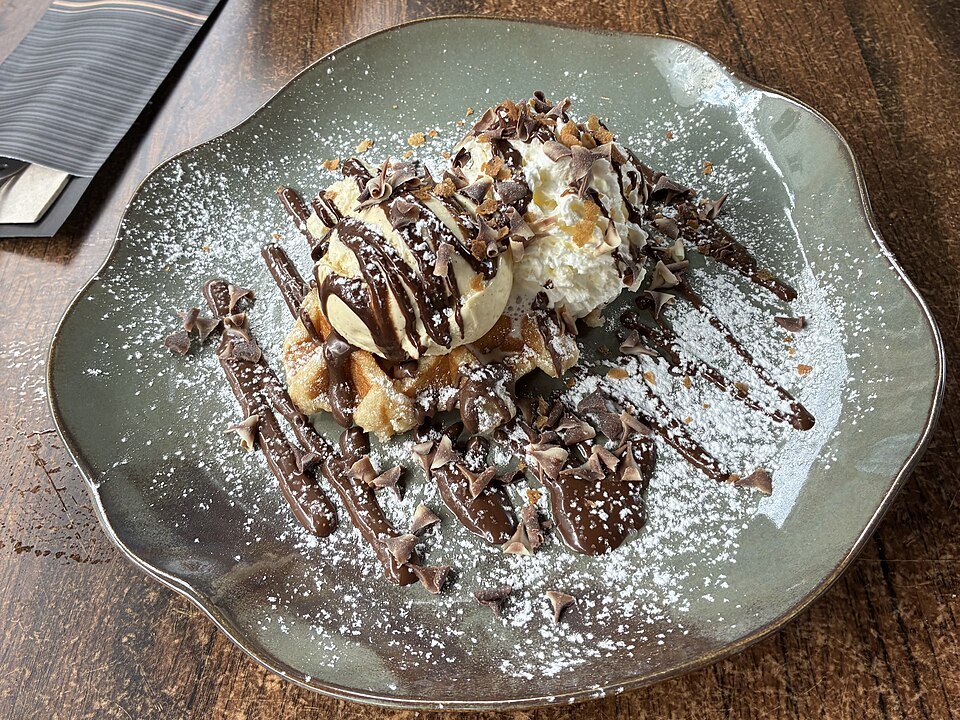 A waffle with chocolate sauce and cream on a plate