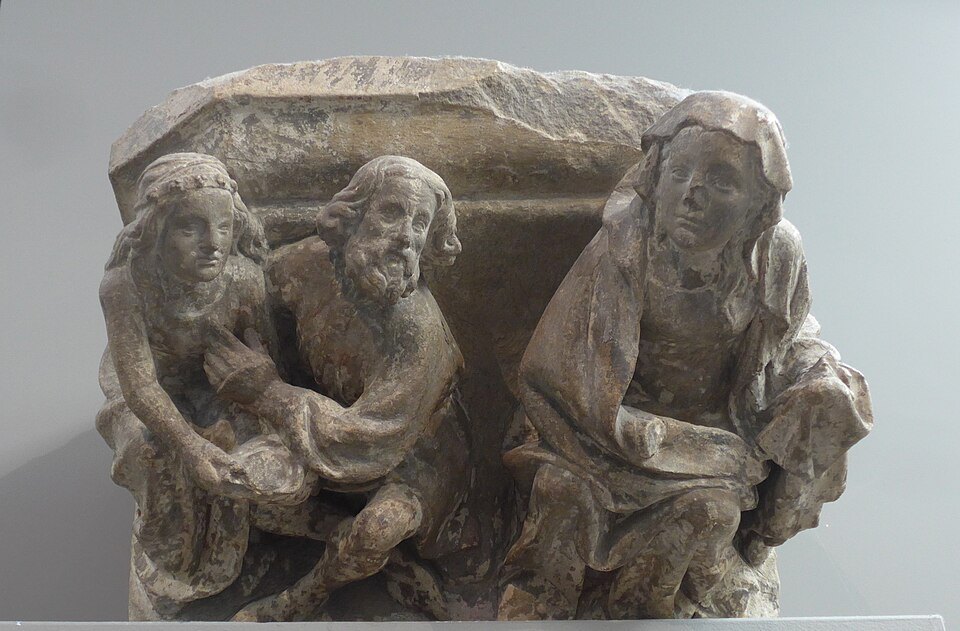 A carved stone fragment with seated figures in a museum
