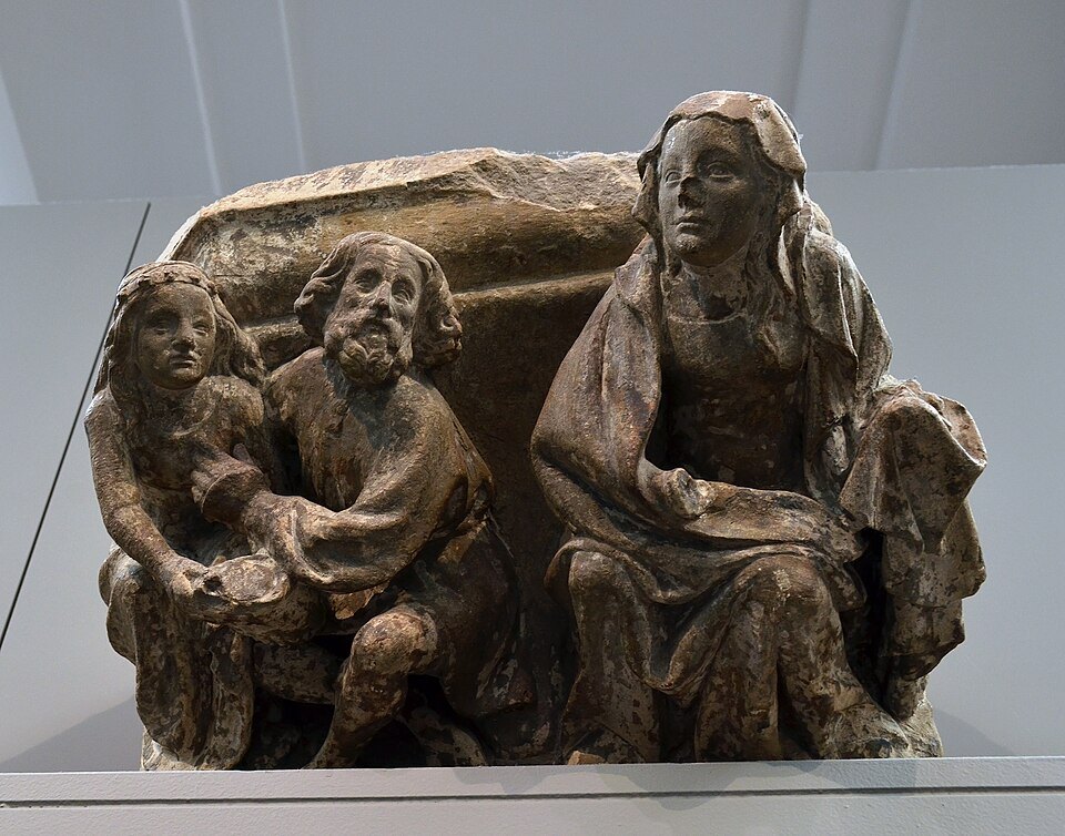 A carved medieval stone group of three figures in the Groeningemuseum