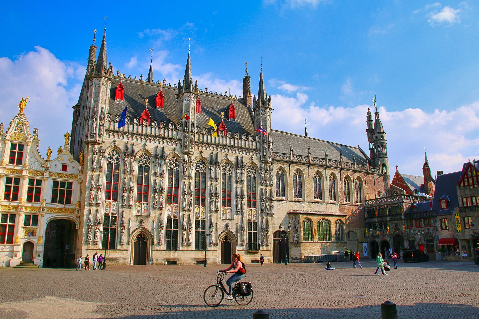 A cyclist crossing the Burg in front of the Gothic City Hall