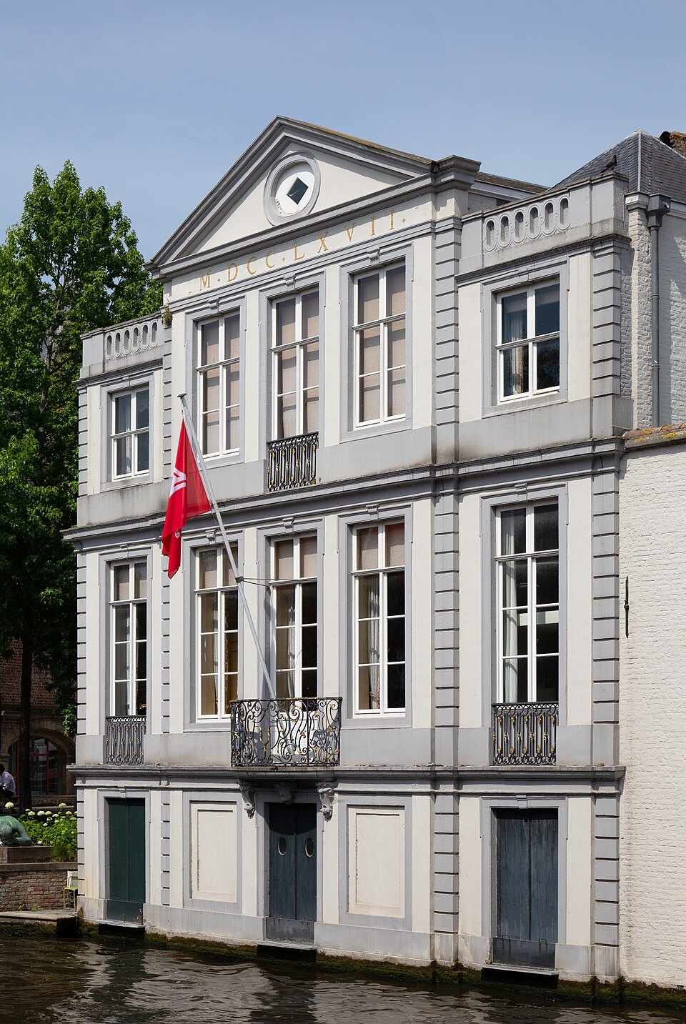 The pale classical front of De Caese house above the canal