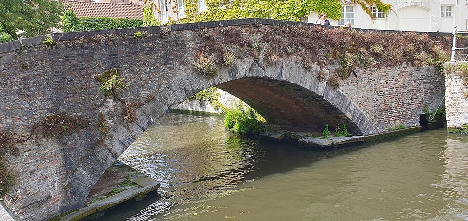 The worn stone arch of the Peerdenbrug close to the water