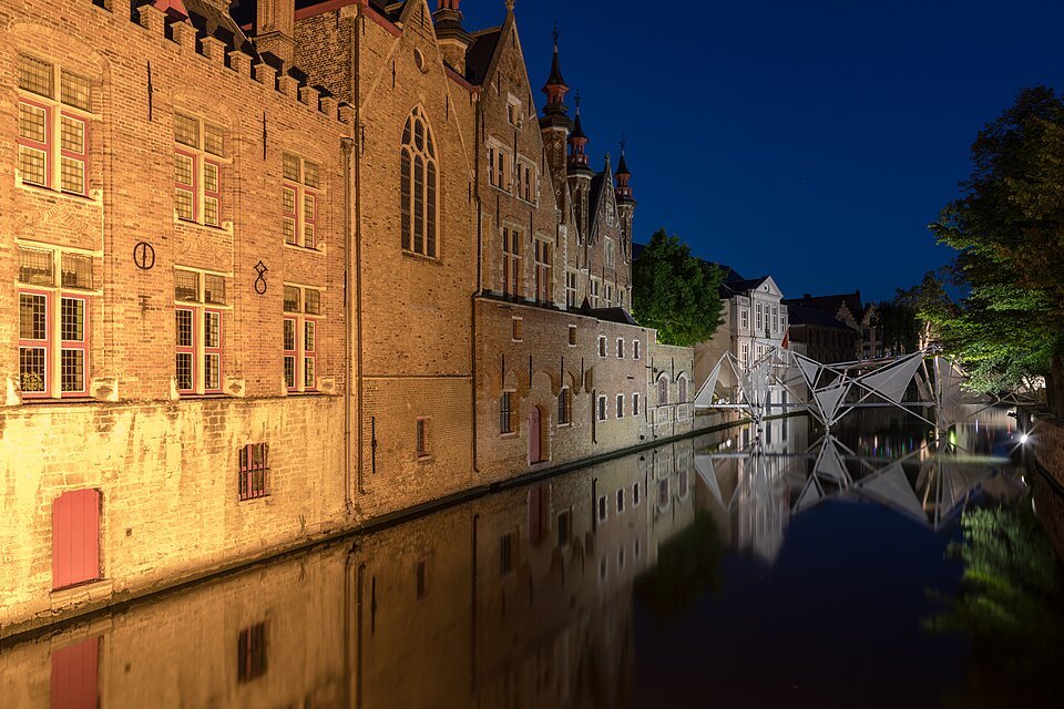 The Groenerei floodlit at dusk, the walls glowing in the still water