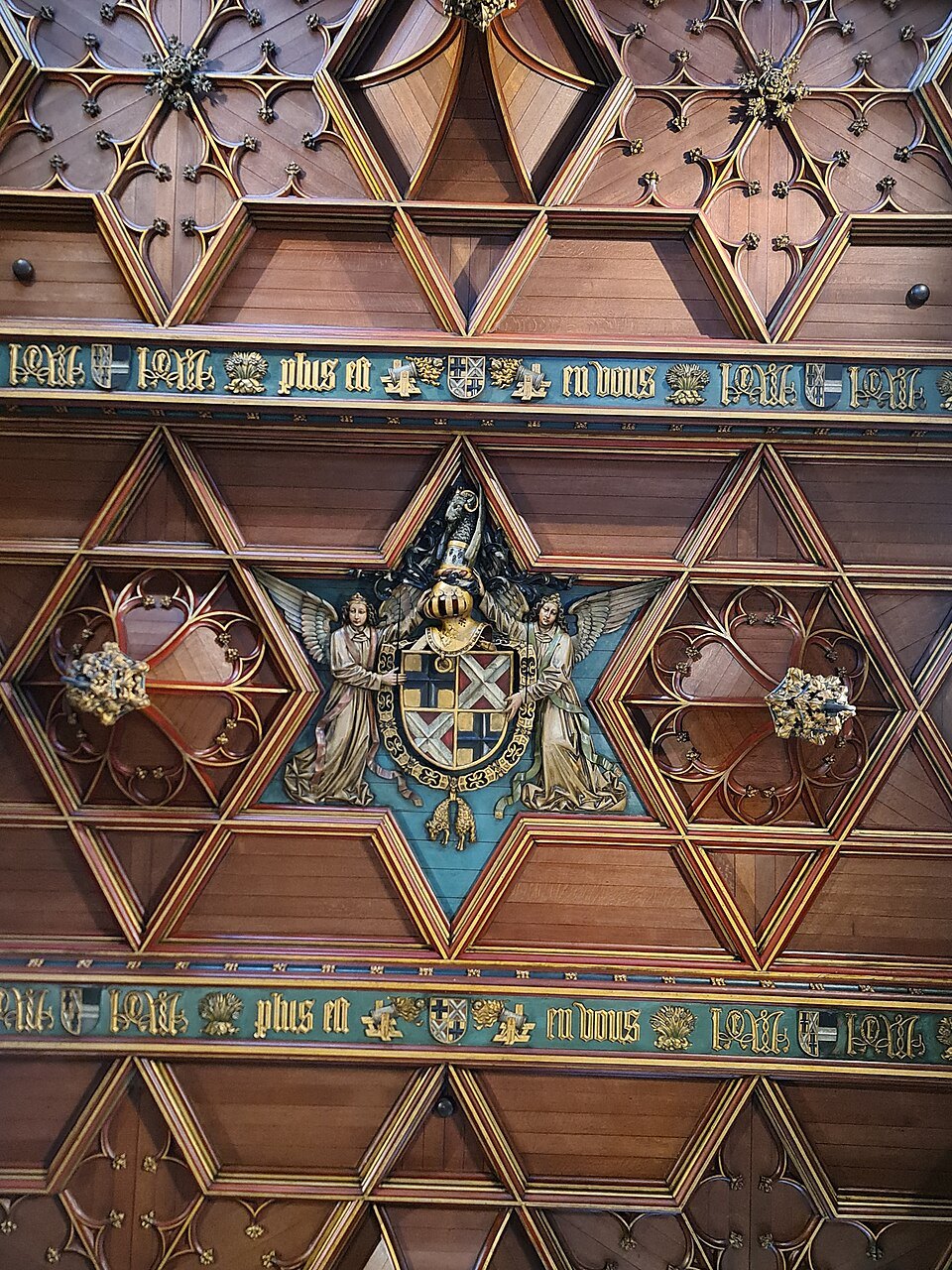 The painted and carved ceiling of the entrance hall, gilded stars set in wooden panels