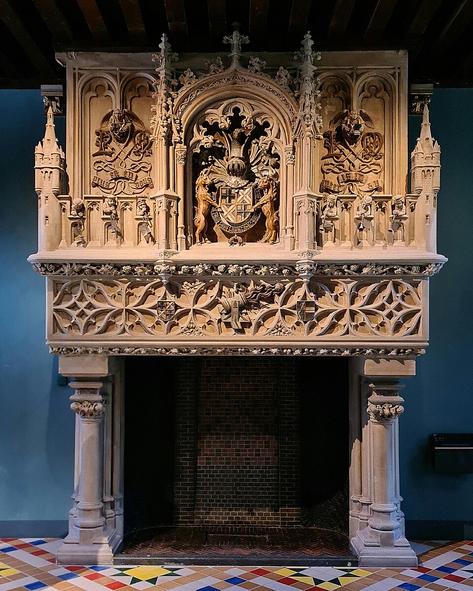 A carved stone chimneypiece with a coat of arms in one of the palace rooms