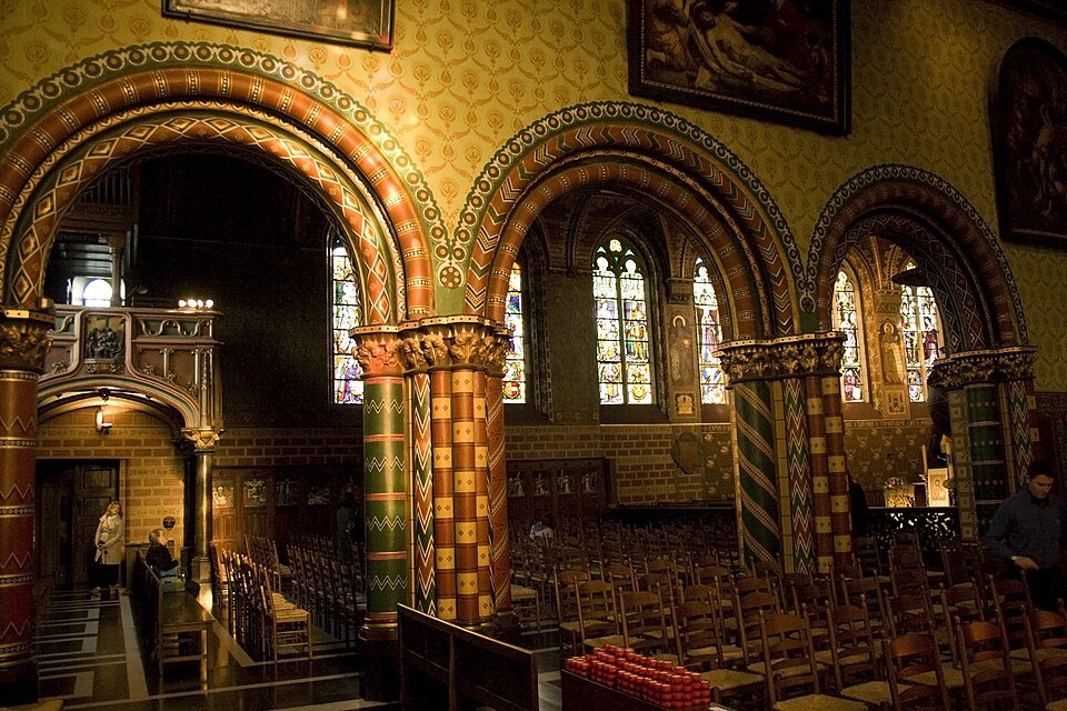 Round arches and painted columns, looking from a side chapel into the upper chapel