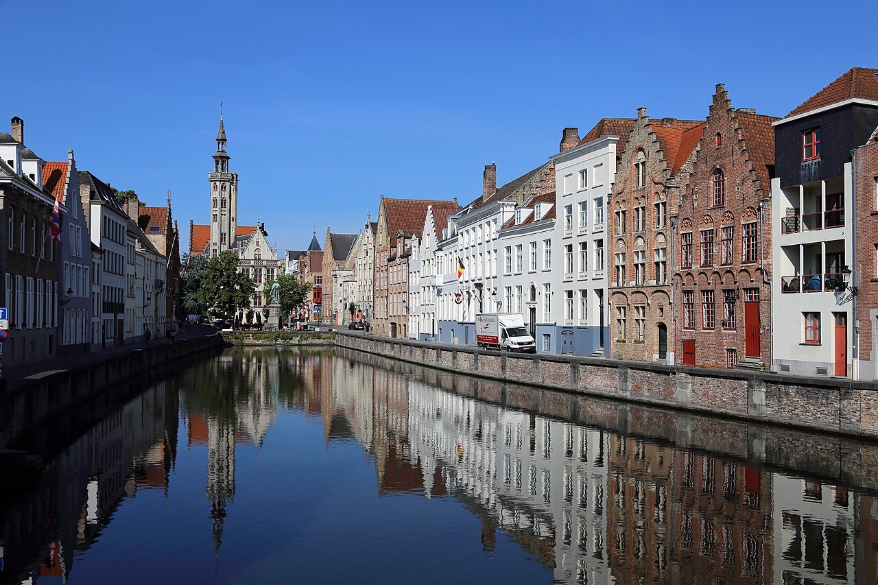 Houses of the Spiegelrei doubled in the still canal, the Poortersloge tower at the end