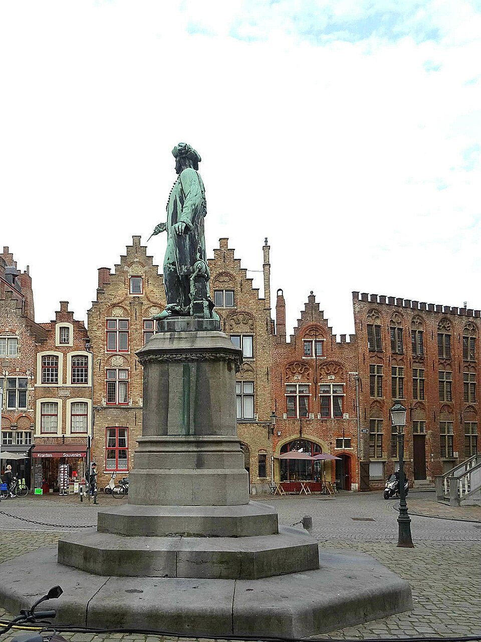 The statue of Jan van Eyck on its pedestal in front of gabled houses