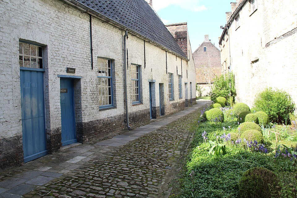 A cobbled lane of the former almshouses with blue doors and a garden