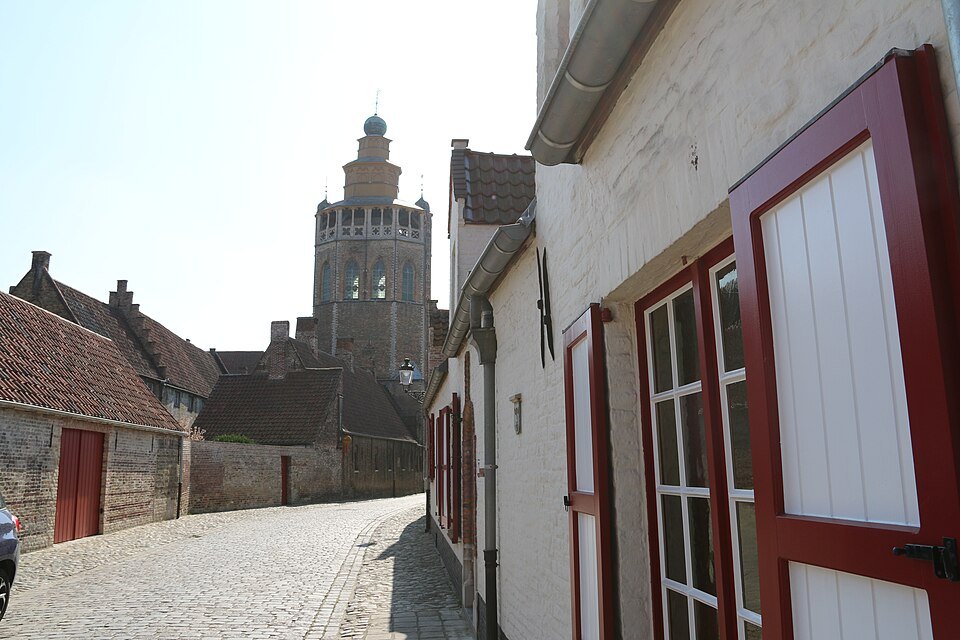 A cobbled street leading to the church tower between whitewashed houses