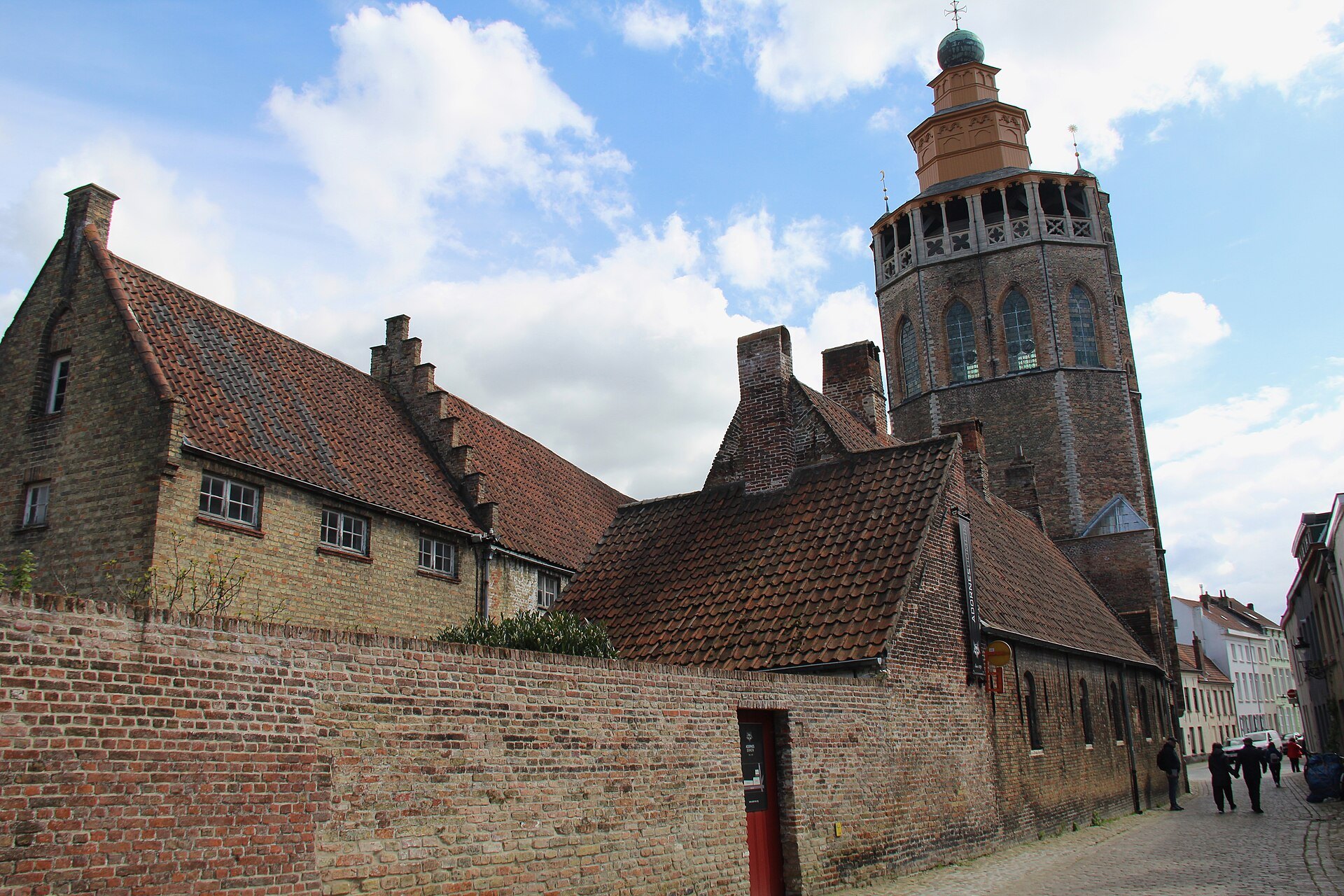 The lantern tower of the Jerusalem Church rising behind a brick wall and stepped gables on Balstraat