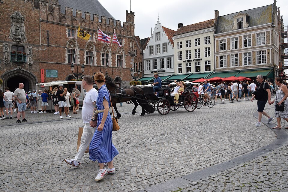Horse carriages and visitors crossing the cobbles of the Markt