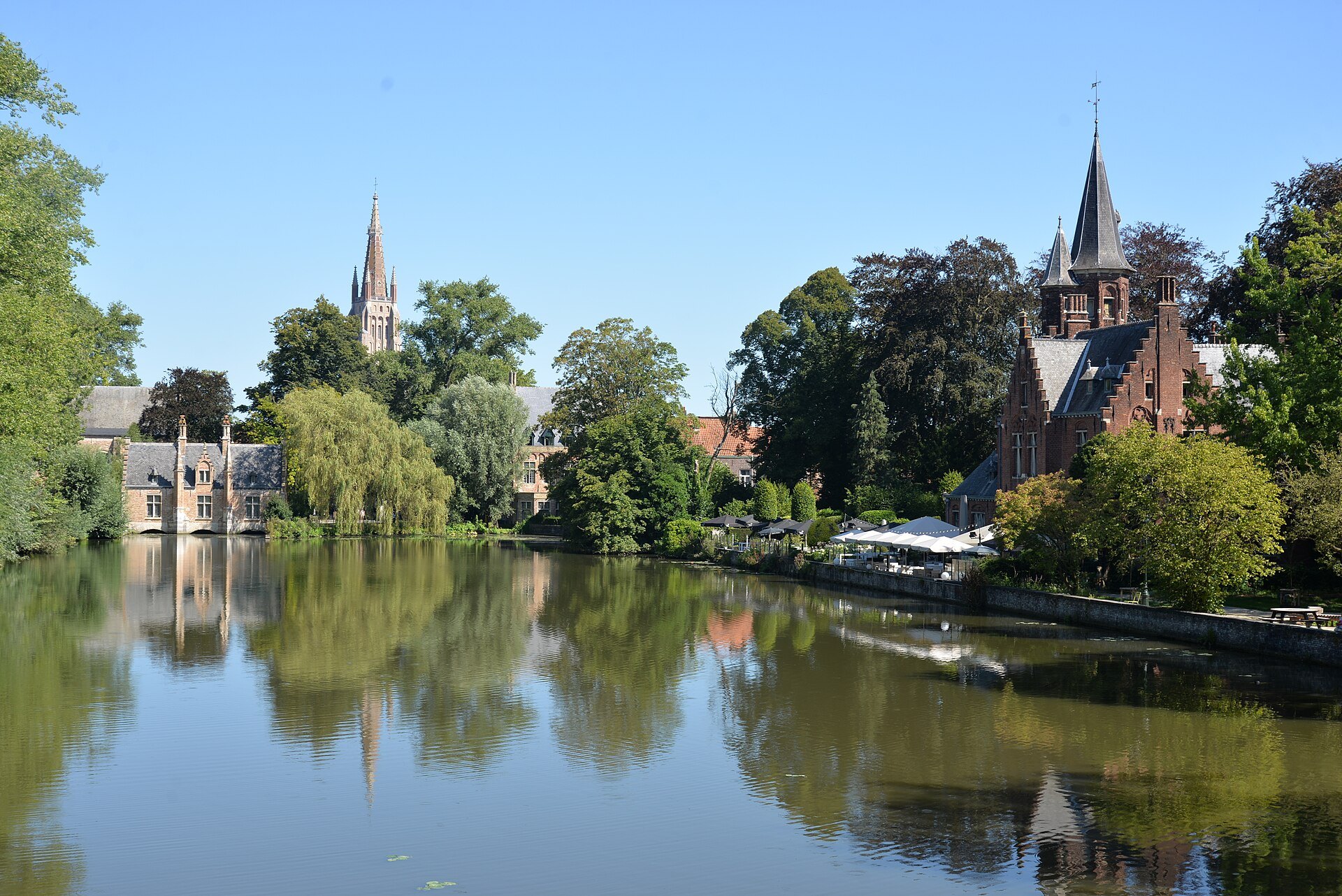 The Minnewater reflecting its trees, the spire of Our Lady and the turret of Kasteel de la Faille