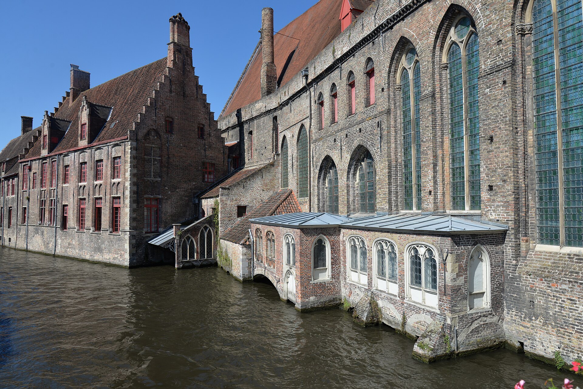 The hospital's medieval brick wards and chapel windows rising straight from the canal