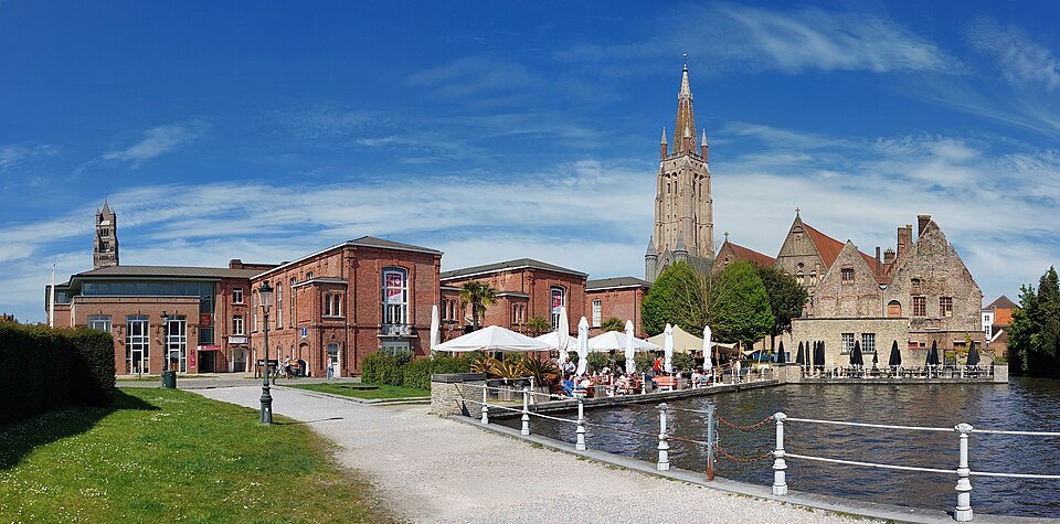 The nineteenth-century hospital buildings and a terrace by the water, the tower of Our Lady behind