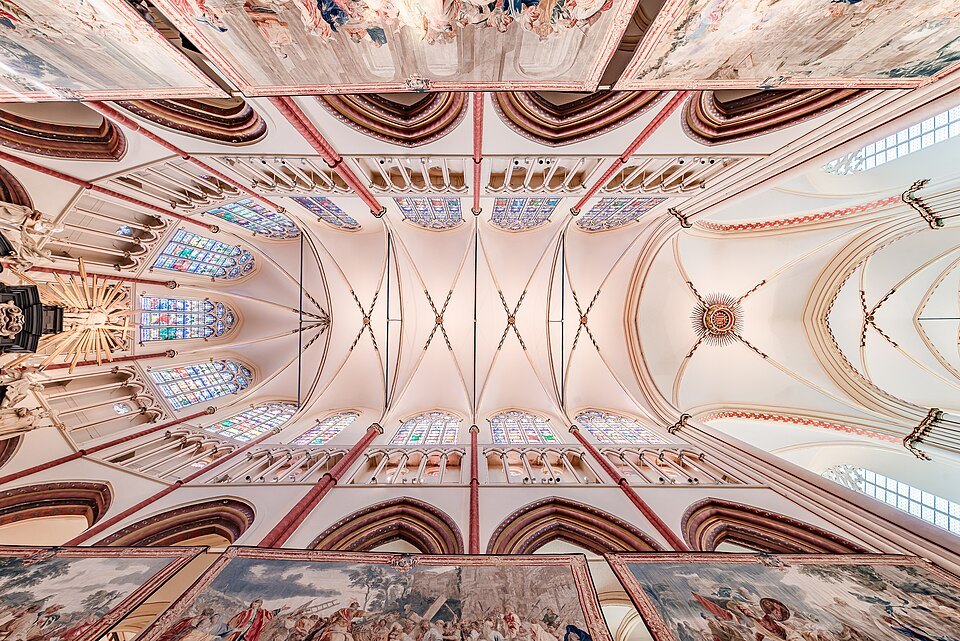 The vaulted ceiling of the nave above a row of tapestries