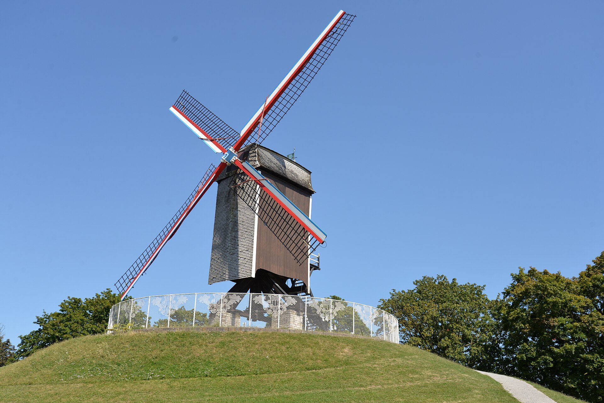 Sint-Janshuismolen on its grassy mound, sails against a clear blue sky